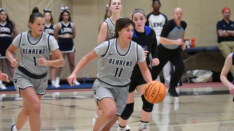 A Penn State Behrend female basketball player dribbles the ball upcourt.