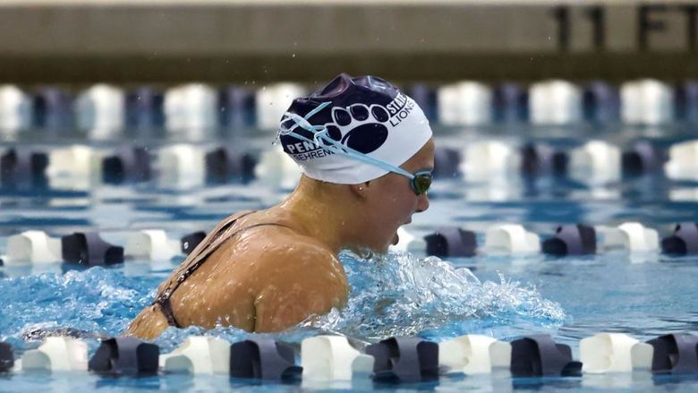 A female Penn State Behrend swimmer competes in a breaststroke race.