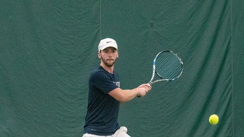 A member of the Penn State Behrend men's tennis team hits a backhand.
