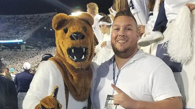 Penn State Behrend alumnus Colten Brown poses with the Nittany Lion at a White-Out game.