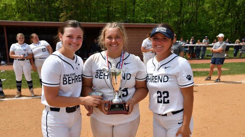 Three Penn State Behrend softball players hold the AMCC runner-up trophy.