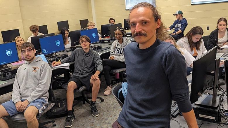 Penn State Behrend faculty member Jasper Sachsenmeier poses in a classroom with several students.
