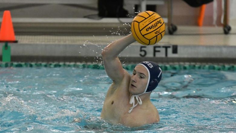 A Penn State Behrend men's water polo player catches the ball.