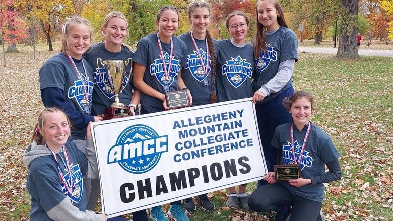 The Penn State Behrend women's cross country team poses with the AMCC championship banner
