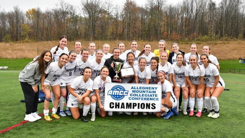 The Penn State Behrend women's soccer team poses with the AMCC championship banner.