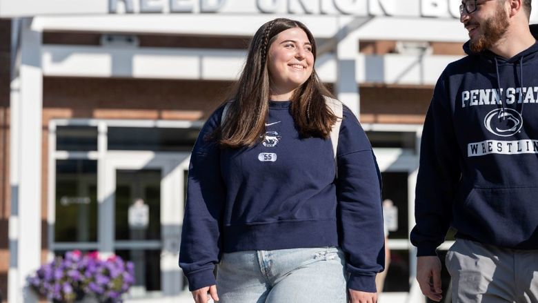 Two students smile while walking outside Penn State Behrend's Reed Union Building.