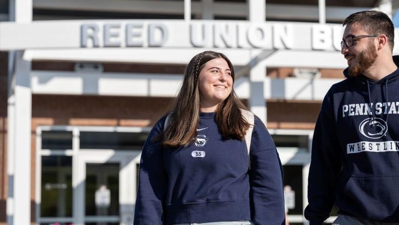 Two students smile while walking outside Penn State Behrend's Reed Union Building.