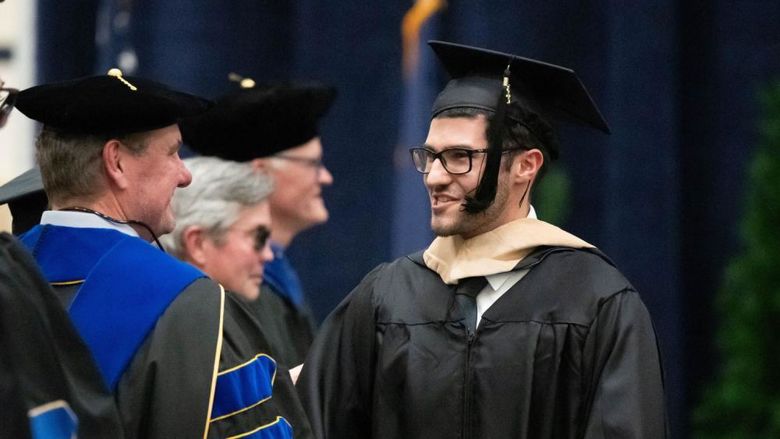 A graduate smiles at a faculty member during Penn State Behrend's commencement program.