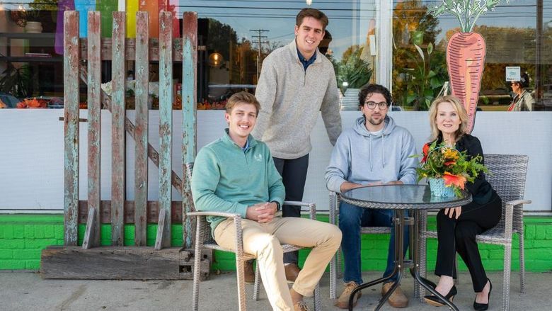 Three Penn State Behrend students pose with the owner of a local cafe.
