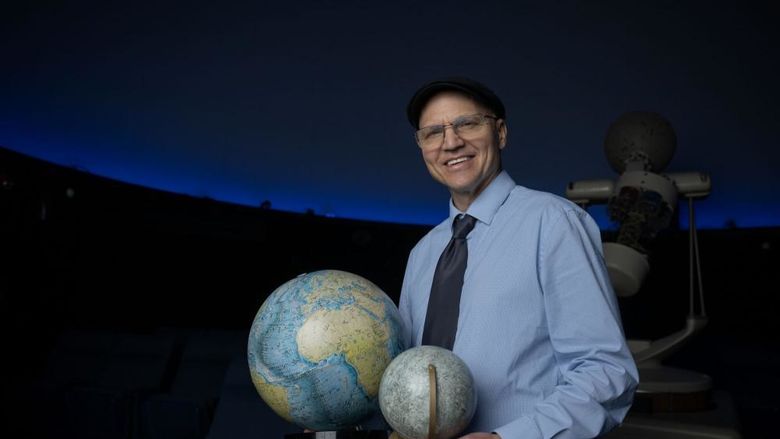 Darren Williams, an astronomer at Penn State Behrend, holds models of the Earth and the moon.