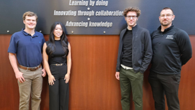 photo of three students and one faculty member in front of Black School of Business sign