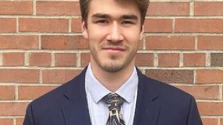 Photo of Michael Del Signore in blue suit against brick wall