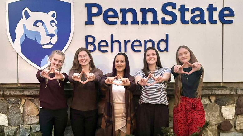 Five female students hold their hands up in the symbol for the Four Diamonds Fund.