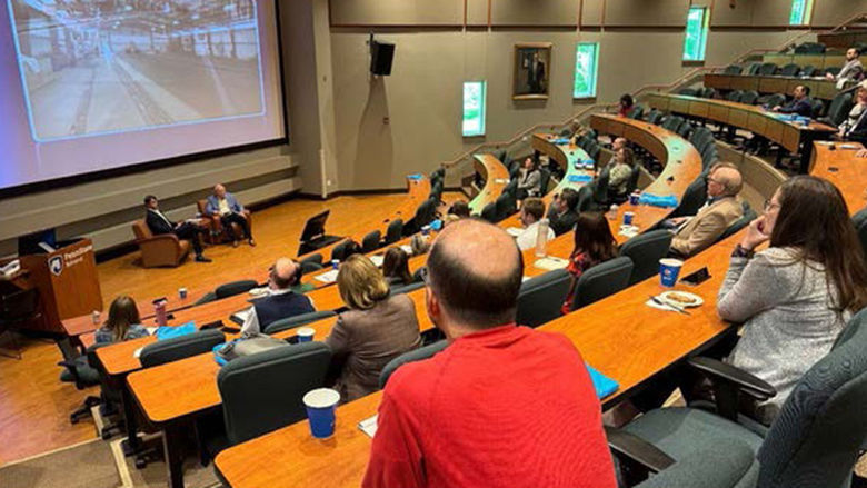 Speakers having a conversation in front of an auditorium of guests