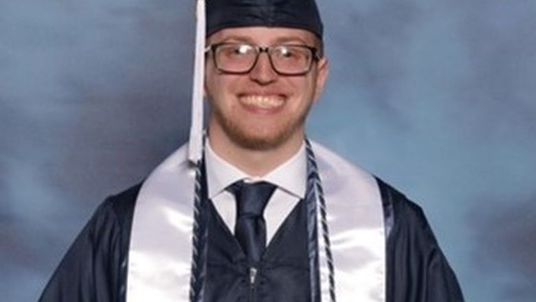 Photo of Tim Keen in Penn State graduation regalia holding diploma