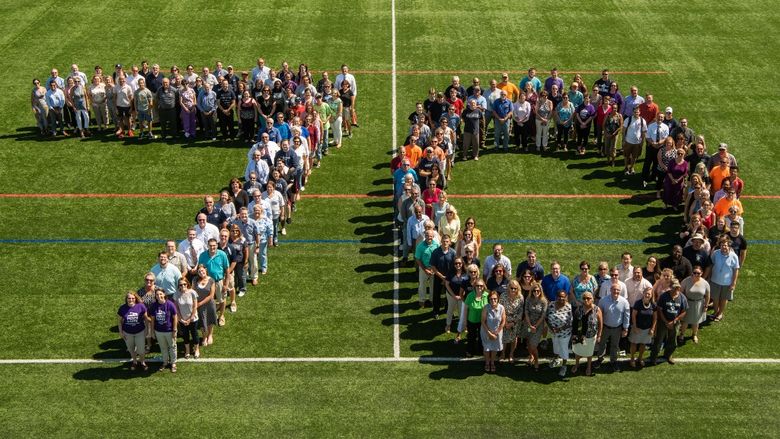Students, faculty and staff form a giant "70" on an athletic field at Penn State Behrend.