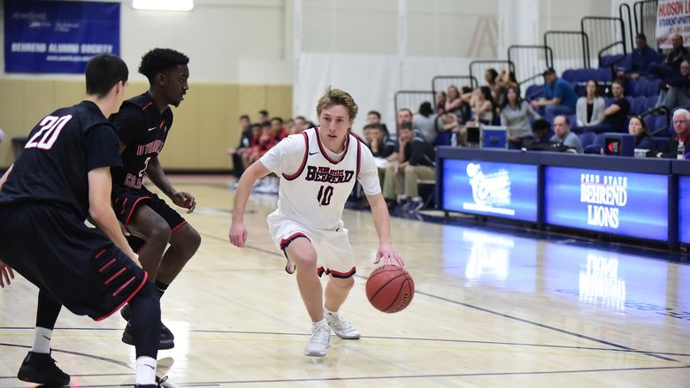 Penn State Behrend basketball player Andy Niland dribbles toward the basket.