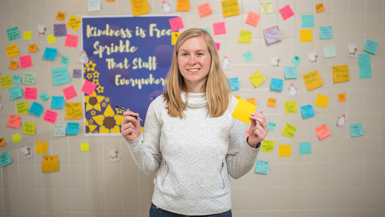 Woman standing in front of a wall of Post-It notes