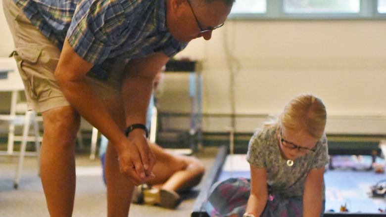 A College for Kids instructor works with a young girl in a Penn State Behrend robotics lab.
