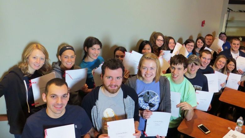 Student volunteers show coloring books they assembled during a Circle K training program at Penn State Behrend.