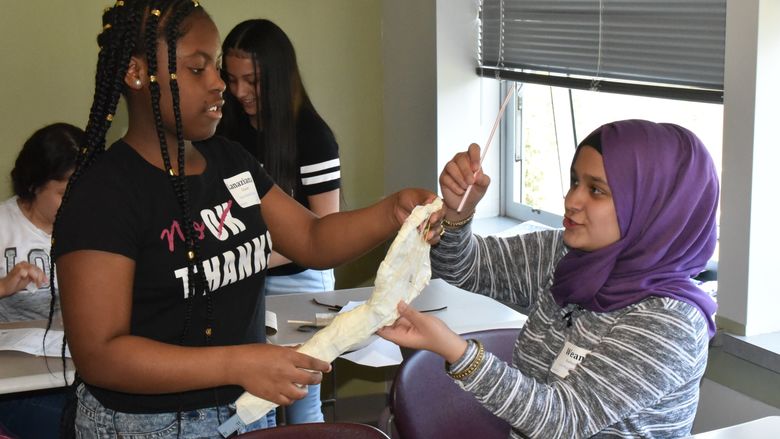 Lanaziana Glover, left, and Weam Kathen, both seventh-grade students at East Middle School, work on building a tennis racket during the "Tennis Anyone?" activity at Math Options Career Day. 