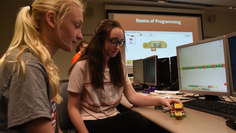 Sydney Rotko, at left, and Sammy Fellows, both students in the General McLane School District, work on programming the alligator they created as part of GE Girls @ Penn State Behrend.