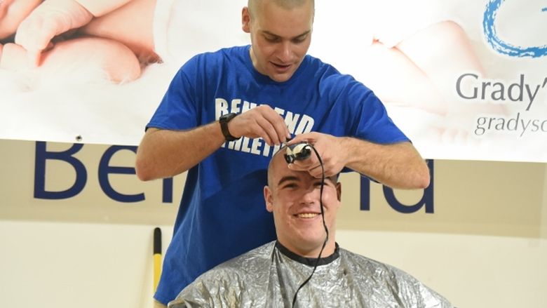 A Penn State Behrend baseball player shaves his teammate's head during a fundraising event.