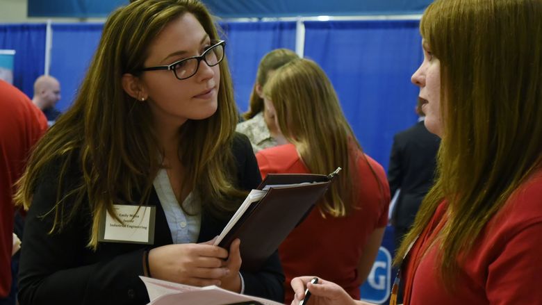 Female student talking to recruiter at job fair.