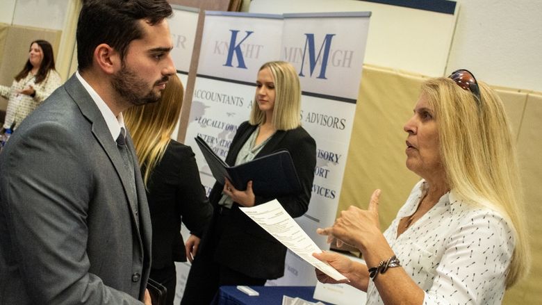 A student talks with a corporate recruiter at the Penn State Behrend fall Career and Internship Fair.