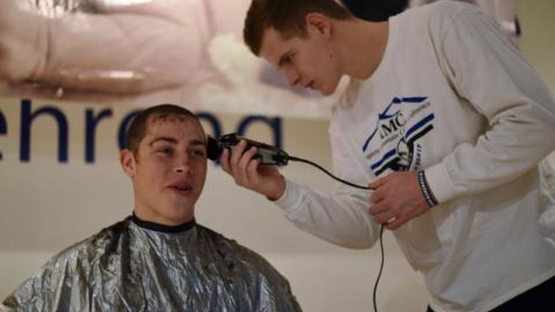 A Penn State Behrend baseball player has his hair cut.