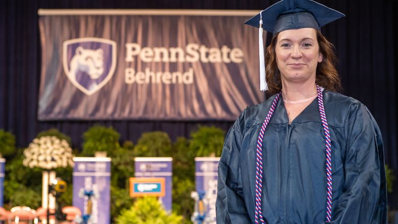 A Penn State Behrend graduate poses on the commencement stage.