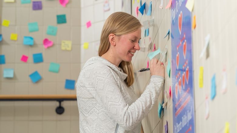 Penn State Behrend alumna Ashlyn Kelly writes on a sticky note in a stairwell of the Reed Union Building at Penn State Behrend.