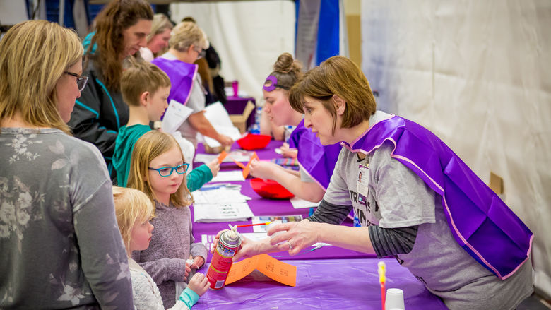 A volunteer teaches children and their parents how to recognize the symptoms of a stroke.