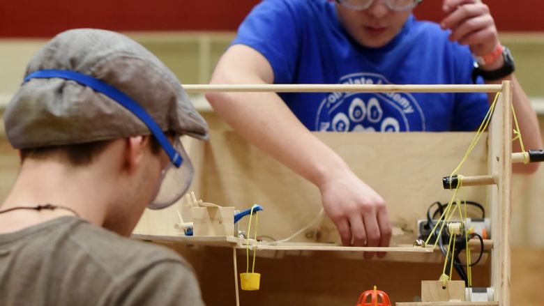 Two high school students test a Rube Goldberg machine during a science event at Penn State Behrend.
