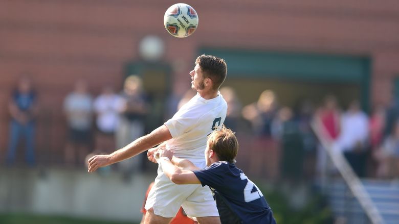 A Penn State Behrend soccer player heads the ball during a game.