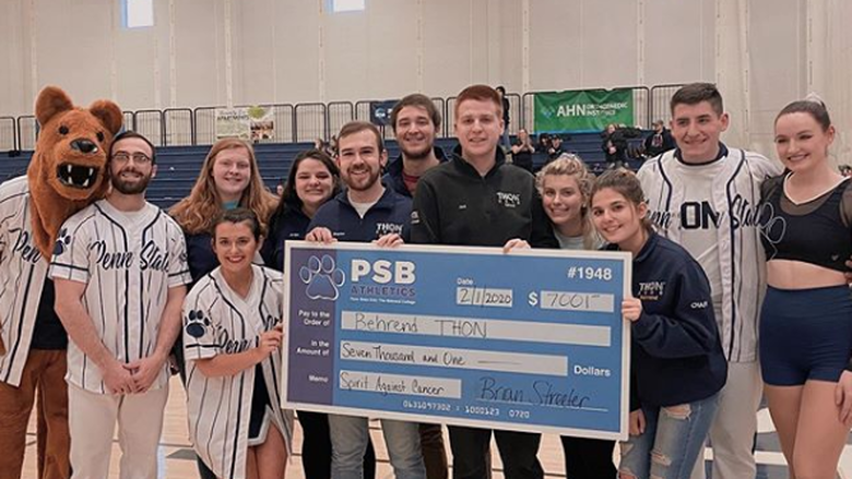 Dance and cheer teams holding a giant check for $7,000 to be donated to THON