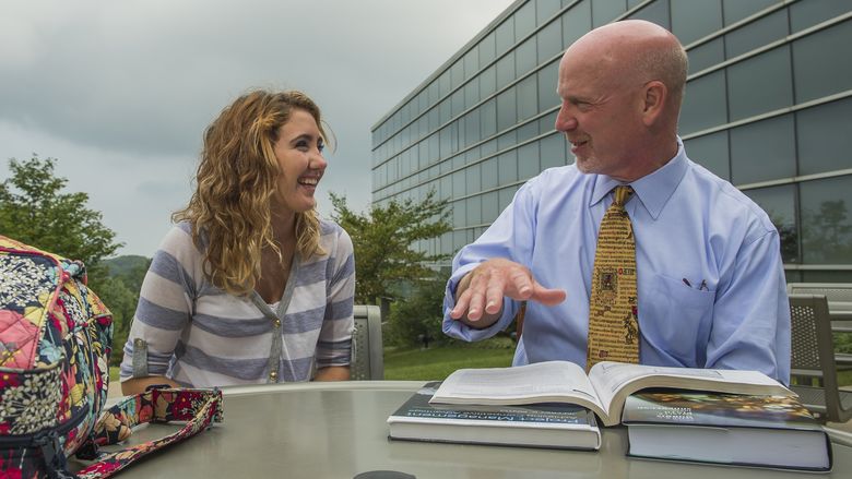 A Penn State Behrend professor works with a student on the Burke Center patio.