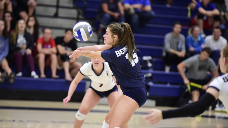 A Penn State Behrend volleyball player digs the ball during a match.