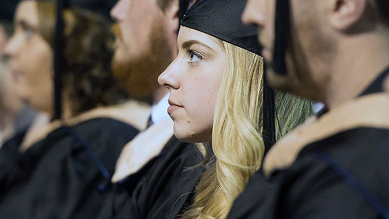 Penn State Behrend students participate in commencement wearing graduation caps and gowns.