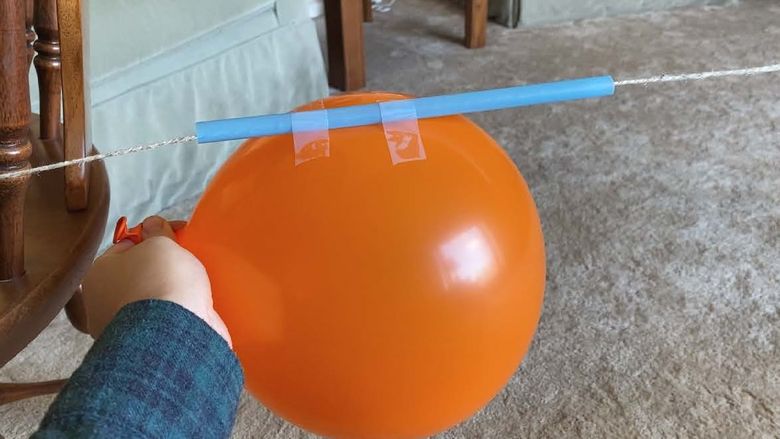 Inflated balloon taped to straw on string