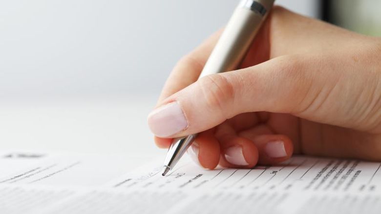 Hand holding pen to complete form