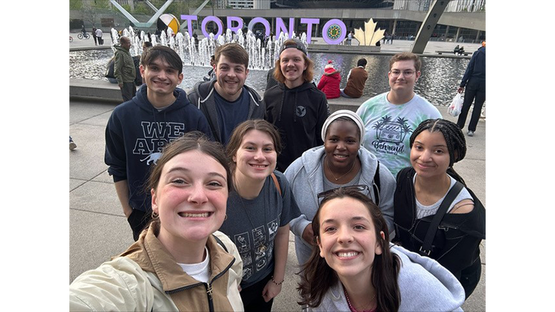 Nine Penn State students pose for a group photo in front of a Toronto sign.