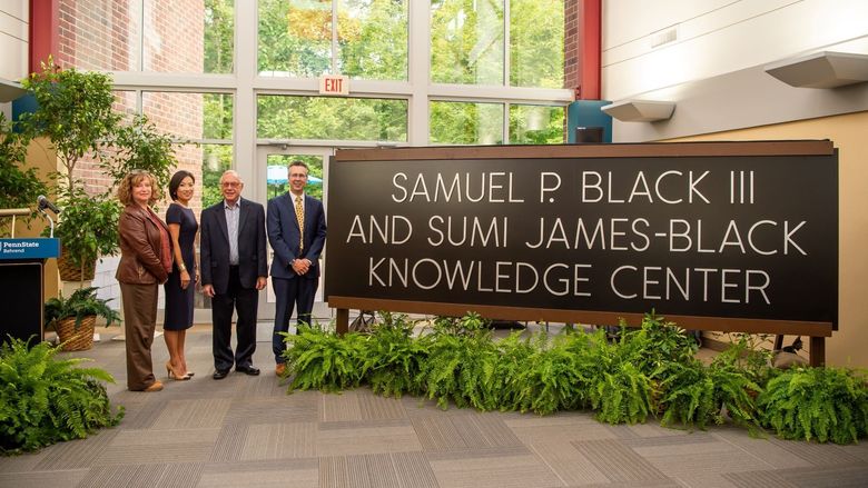 Four officials stand next to a new sign for the Samuel P. Black III and Sumi James-Black Knowledge Center at Penn State Behrend.