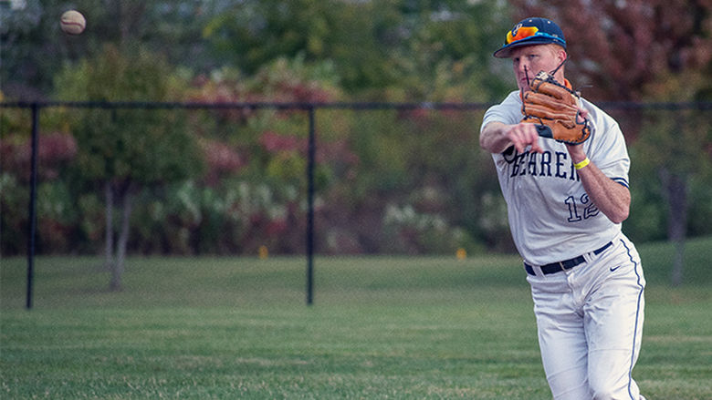 A Penn State Behrend baseball player fields the ball.