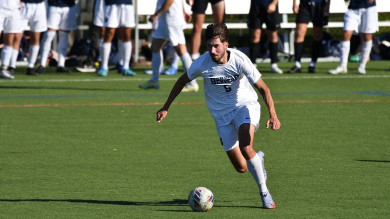 A Penn State Behrend men's soccer player advances the ball up midfield.
