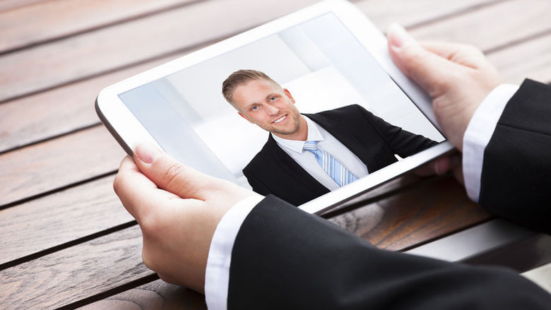A recruiter talks with a job applicant via a tablet.