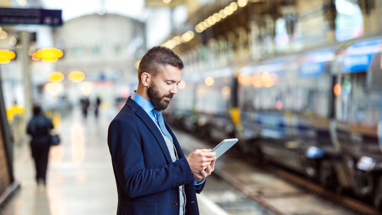 A man checks his smartphone on a subway platform.