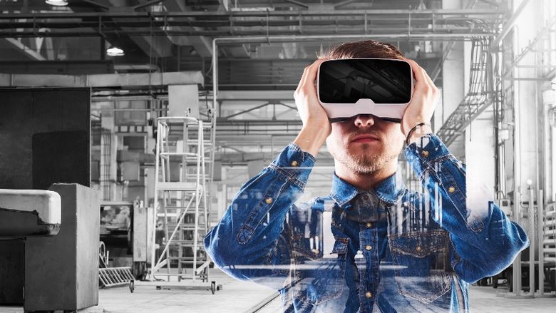 A man in a warehouse looks through a virtual-reality headset.