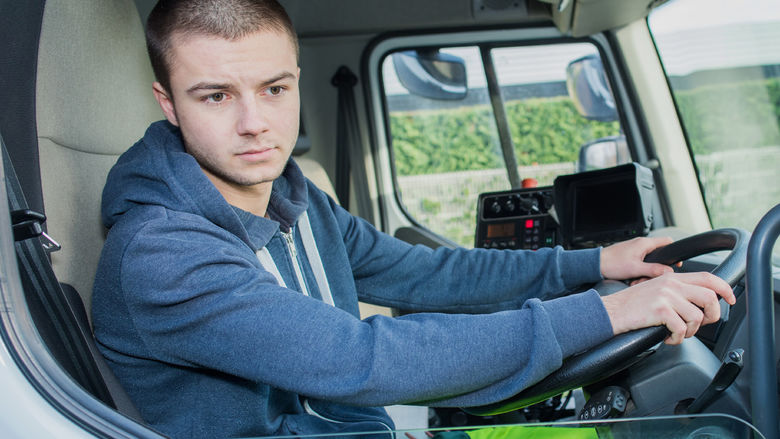 A stock photo of a driver looking out the window of his cab.