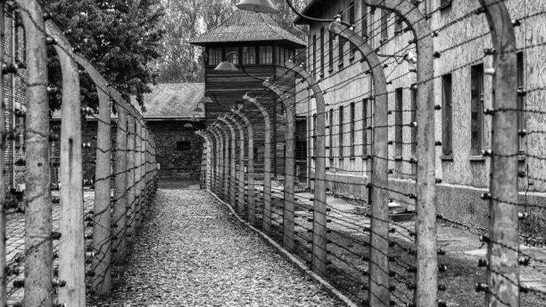 A black-and-white image of an outdoor passageway at a World War II concentration camp.
